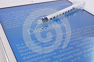 Syringe on a tablet with article about diabetes