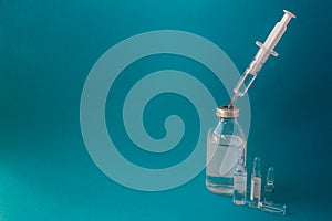 Syringe with a vaccine in a glass bottle on a blue background, close-up