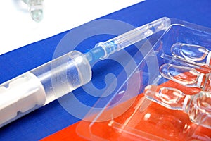 Syringe with a vaccine is held by  hand in a glove on background of the Russian Federation flag