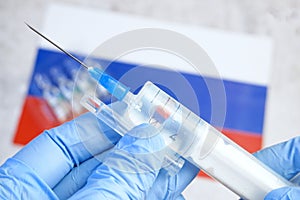 syringe with a vaccine is held by hand in a glove on background of the Russian Federation flag, vaccine