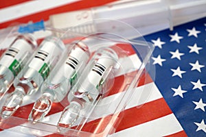 Syringe with a vaccine is held by  hand in a glove on background of the USA flag, vaccine against coronavirus, Operation Warp photo