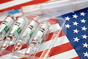 Syringe with a vaccine is held by  hand in a glove on background of the USA flag, vaccine against coronavirus, Operation Warp