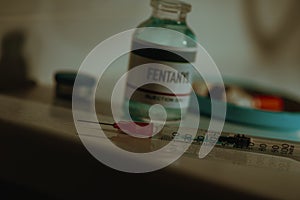 syringe and vial of fentanyl in a sordid bathroom