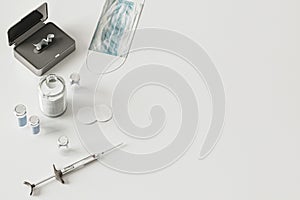 Syringe, vials, face mask on white background from above, coronavirus vaccination concept, medical supplies equipment on table,