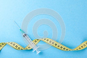 Syringe with yellow measuring tape. Injections for body beauty and weight loss. Drug for muscle growth of bodybuilders