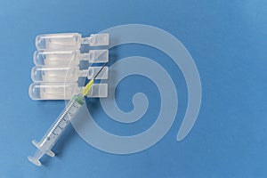 Syringes with ampules of physiological serum on a blue background