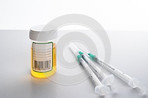 Syringes and medical bottle with yellow liquid laying on white table in hospital. photo