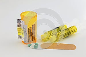 Prescription bottle with warning labels, pills, syringe, supplies