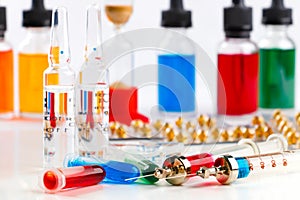 Syringes with medication, ampoules and vials, blister pack and bottles with colored fluid on white background