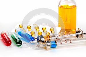 Syringes with medication, blister pack, vials and bottle with colored fluid on white background