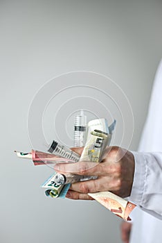 Syringes and money in doctor's hands