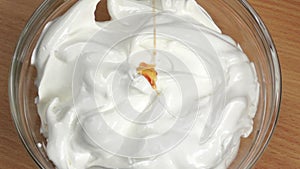 Syrup drops are added to white whipped cream. Slow motion