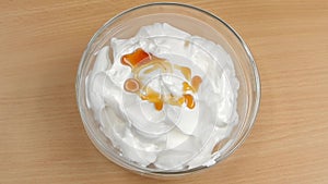 Syrup poured whipped thick cream in slow motion, top view