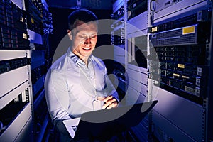 Sysadmin working on notebook computer in server room