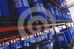 System of address storage of products, materials and goods in a warehouse. blue plastic barrels for storage of chemical liquids.