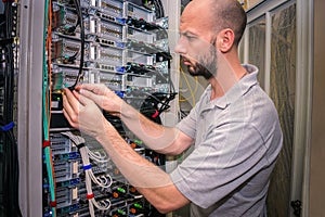 The system administrator works in the data center. Portrait of a technician working with computer equipment. Network engineer