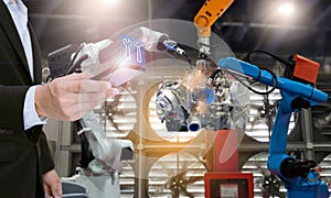 System engineer with smartphone control automation robot arms the production of factory parts engine manufacturing industry robots
