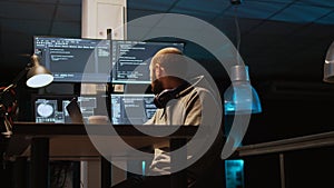 System programmer typing source code on laptop and multiple monitors