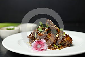 Szechuan Chicken which is a popular Indo-Chinese non vegetarian recipe. served in a plate with chilli sauce. selective focus photo