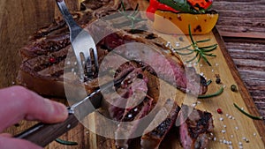 T- bone steak cut into pieces with a knife on a cutting board. Close up