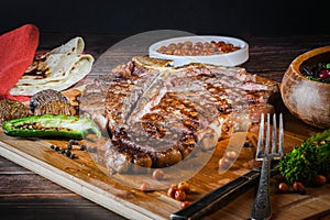 T-bone steak or porterhouse grilled in pieces on wood with hot pepper and salad