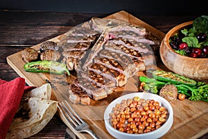 T-bone steak or porterhouse grilled in pieces on wood with hot pepper and salad