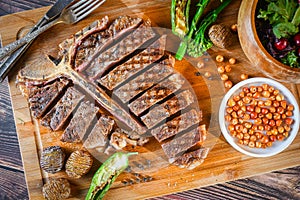 T-bone steak or porterhouse grilled in pieces on wood with hot pepper and salad