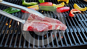 T- bone steak put on cast iron grill barbecue. Slow motion