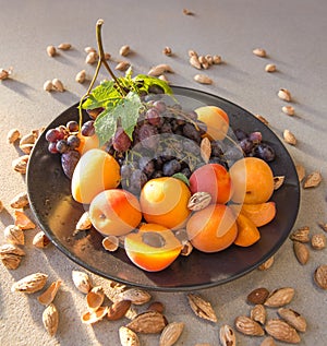 Fruit plate with grapes, apricot and almond on black plate