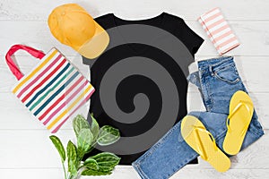 T shirt black and slippers. T-shirt Mockup flat lay with summer accessories. Hat, bag, yellow flip flops on wooden floor