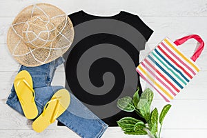 T shirt black and slippers. T-shirt Mockup flat lay with summer accessories. Hat, bag, yellow flip flops on wooden floor