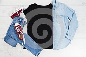 T shirt black and sneakers. T-shirt Mockup flat lay with summer accessories. Jeans and sneakers on wooden floor background. Copy