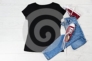 T shirt black and sneakers. T-shirt Mockup flat lay with summer accessories. Jeans and sneakers on wooden floor background. Copy