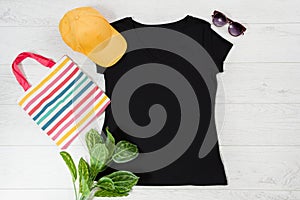 T shirt black. T-shirt Mockup flat lay with summer accessories. baseball hat, bag and sunglasses on wooden floor background. Copy