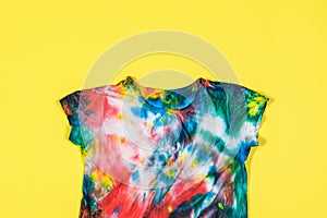 T-shirt with short sleeves in tie dye style on a yellow background. Flat lay.