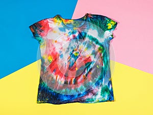 T-shirt in tie dye style on a background of three bright colors. Flat lay.