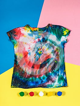 T-shirt in tie dye style and paint on a three-color background. Flat lay.