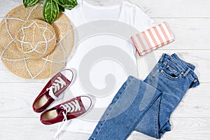 T shirt white and sneakers. T-shirt Mockup flat lay with summer accessories. Hat, jeans and sneakers on wooden floor background.