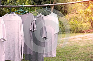 T-shirts hanging on wooden bar for dry after cleaning clothes in the garden outdoor