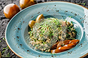 Tabbouleh salad with bulgur, seedlings, tomatoes and olives in plate on dark background.