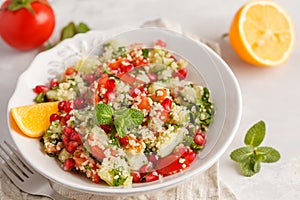 Tabbouleh salad with tomato, cucumber, couscous, mint and pomegranate. Vegan Healthy Food Concept. Traditional middle eastern or