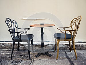 A table with 2 chairs next to a wall. Street cafe in the center of Bucharest city