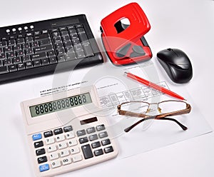 Table accounting: invoice, keyboard, calculator, mouse, hole punch, glasses and red pen