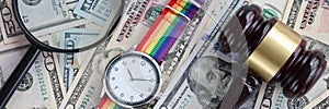 On table are American banknotes magnifying glass lgbt watch and wooden gavel. photo