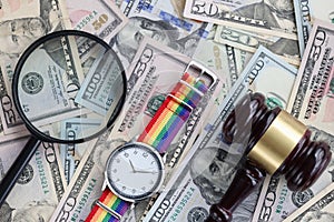 On table are American banknotes magnifying glass lgbt watch and wooden gavel. photo