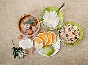 Table Appointments for Healthy Organic Breakfast.Walnuts,Oatmeal and Cottage Cheese.Cut orange and Apple.Green Ceramic and Wooden