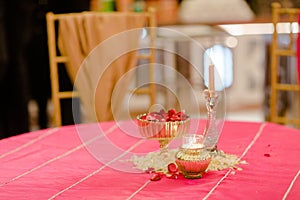 Table arrangement with a vase filled with flower petals and lit candles