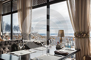 Table with a bar in the restaurant with panoramic windows. Elegant appearance, wine glasses, chic romantic atmosphere, bright day