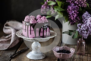 On the table is a beautiful chocolate cake and a bouquet of lilacs. dark