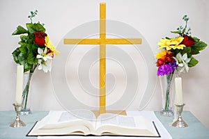 Table for a bible in a rustic Catholic church. Candles and artificial flowers